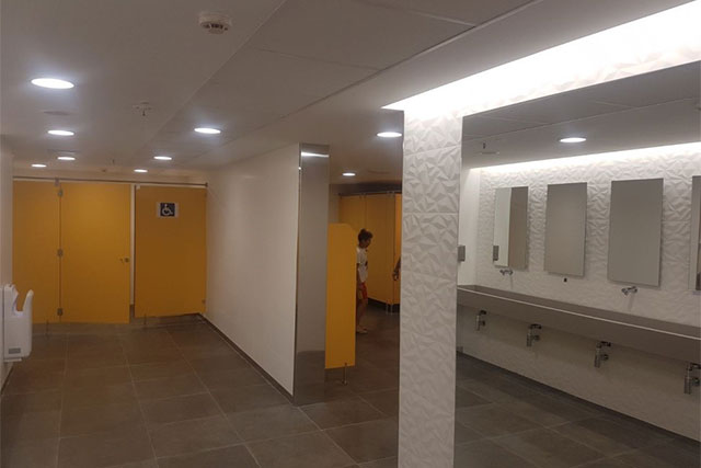 fotografía de unos baños públicos modernos y amplios hechos con pladur, escayola y techos con iluminación indirecta